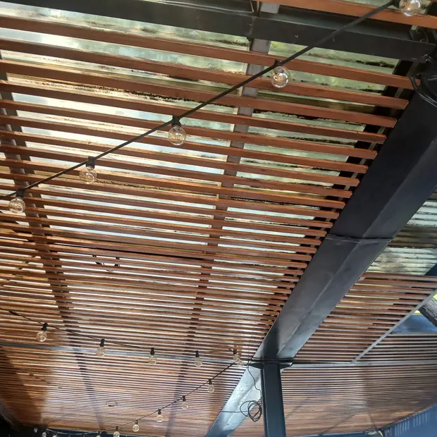 Timber slat roof with festoon lighting over an entertainment area in Fourways by Impi Teak